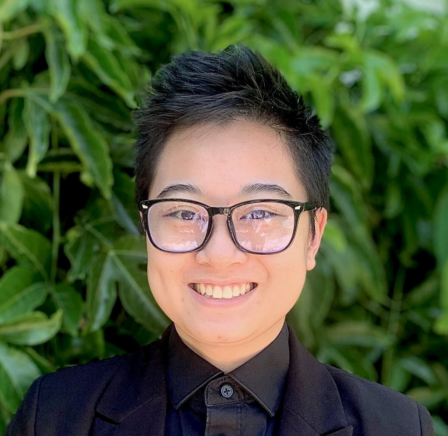 A picture of Kip smiling. She is wearing a black shirt and aviator sunglasses.